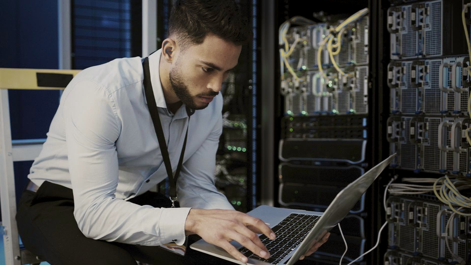 Stand-in footage: an engineer kneels at an open rack and works on a laptop. The rack is measured unit by unit, then drawn as a front elevation.